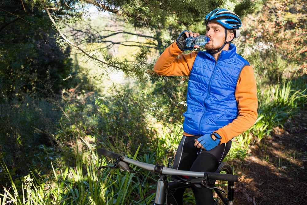 Male mountain biker drinking water in the forest