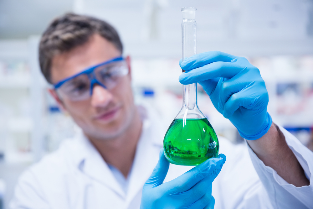Chemist holding up beaker of green chemical in the laboratory